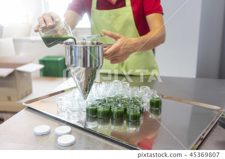 Woman filling wheatgrass smoothie in glasses 45369807