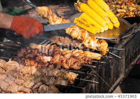 Hands turning skewers with pieces juicy fragrant 45371903