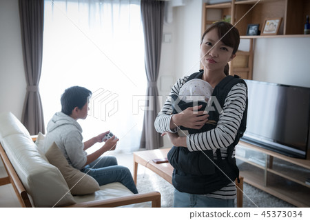 Wife holding a baby annoyed by her husband who does not raise her baby 45373034