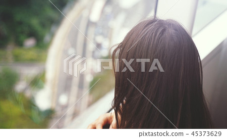 Young brunette woman looking through the window. urban city view with buildings and roads. Young brunette woman looking through the window. urban city view with buildings and roads. 45373629
