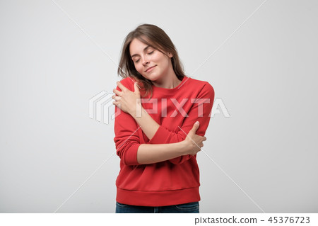 young girl in red shirt hugging herself. 45376723