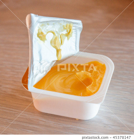 Cheese sauce in plastic cap on wood table Cheese sauce in plastic cap on wood table 45378147