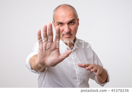Mature man in yellow shirt showing sign stop 45378256