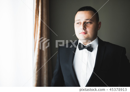 Grooms morning preparation. Handsome man getting dressed and preparing for the wedding Grooms morning preparation. Handsome man getting dressed and preparing for the wedding 45378913