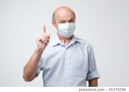 Mature man in protective mask pointing finger up. Mature man in protective mask pointing finger up. 45379296