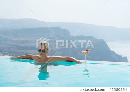 Young woman relaxing in the pool with a gorgeous view on Santorini. Young woman relaxing in the pool with a gorgeous view on Santorini. 45380264