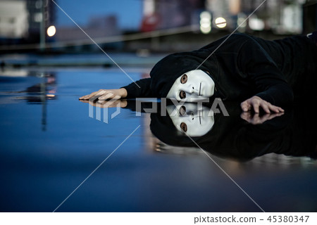 Mystery man in white mask lying on wet floor 45380347