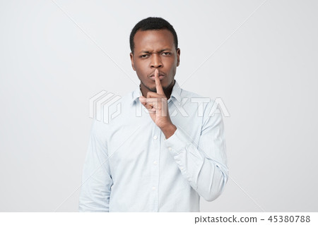 Serious african male keeps index finger on lips Serious african male keeps index finger on lips 45380788