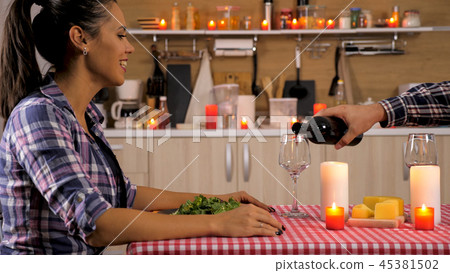 Beautiful young wife having a sweet moment with her husband while enjoying dinner Beautiful young wife having a sweet moment with her husband while enjoying dinner 45381502