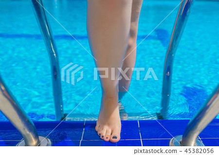 A woman getting out of the blue water in the pool. A woman getting out of the blue water in the pool. 45382056