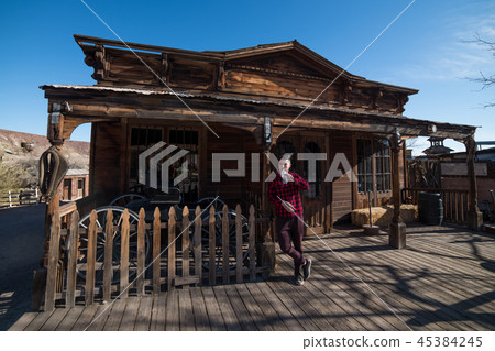 Man drinking water in front of old wooden house in 45384245