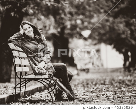 Style girl sitting at bench in autumn park. 45385029