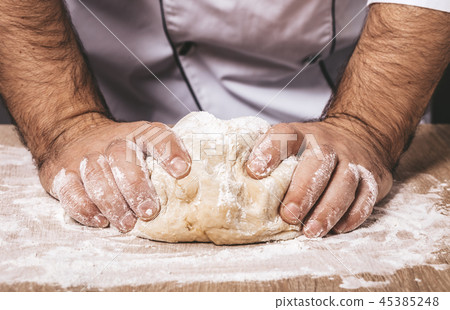 male chef kneads the dough 45385248