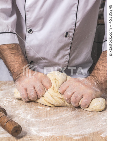 male chef kneads the dough 45385249