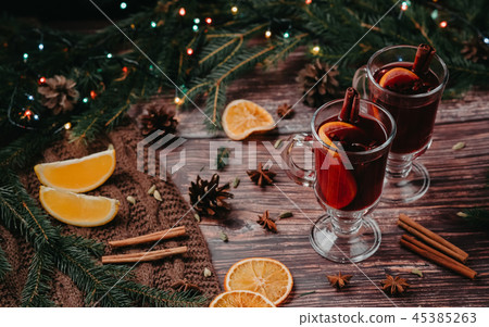 Two glasses of Christmas mulled wine with spices and orange slices on a wooden rustic table Two glasses of Christmas mulled wine with spices and orange slices on a wooden rustic table 45385263