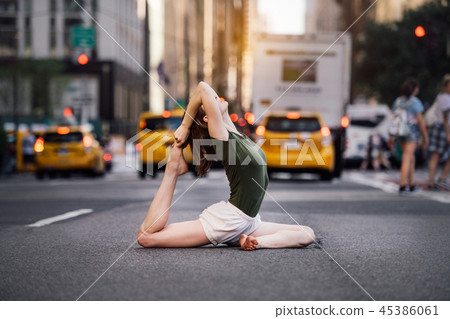 Woman doing yoga pose on city street Woman doing yoga pose on city street 45386061