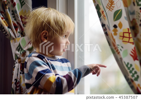 Little boy standing near window  45387507