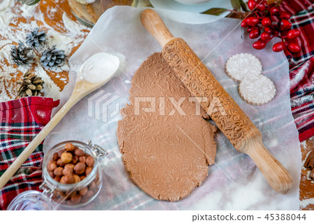 Rolling pin with a pattern on a wooden decorated table covered with baked flour. Rolled dough with a Rolling pin with a pattern on a wooden decorated table covered with baked flour. Rolled dough with a 45388044