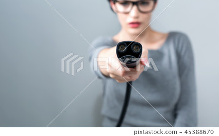 Young woman with an electric vehicle charger 45388670