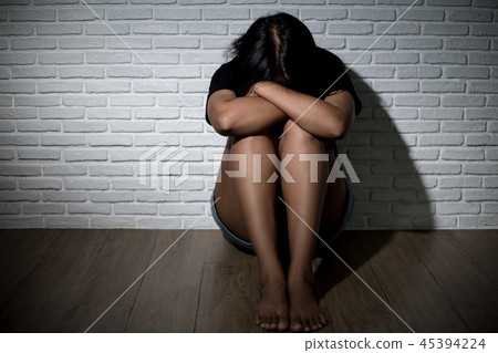 Sad young woman  sitting near the wall. 45394224