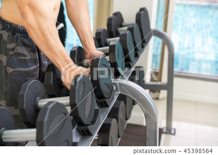 Muscular man bodybuilder training with dumbbells. 45398564