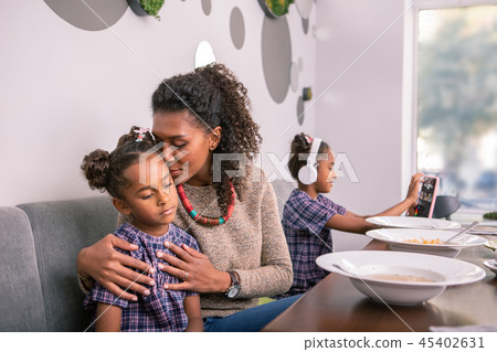 Loving curly dark-haired mother hugging her little cute girl Loving curly dark-haired mother hugging her little cute girl 45402631