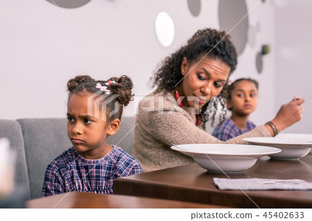 Cute dark-eyed daughter feeling emotional having lunch with mom Cute dark-eyed daughter feeling emotional having lunch with mom 45402633