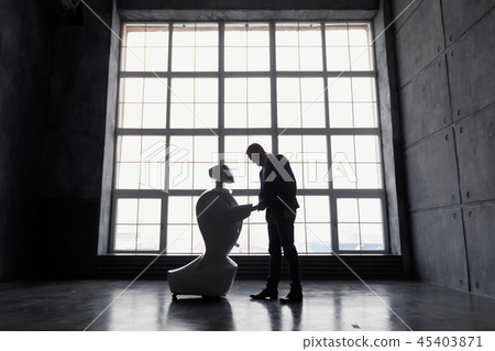 A man communicates with a robot, with cardboard box in hand. delivery concept. silhouette of the 45403871