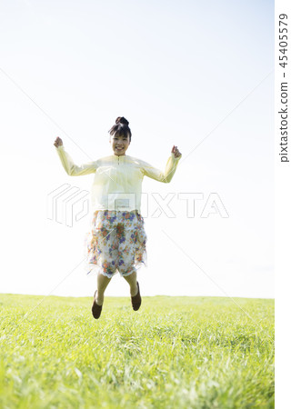 A woman who jumps in the meadow 45405579