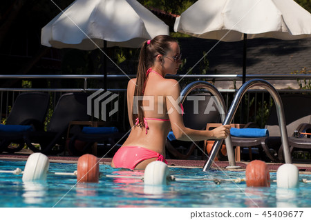 Wet woman leaving swimming pool Wet woman leaving swimming pool 45409677