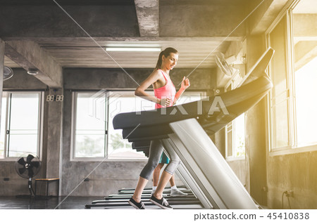Woman running on treadmills doing cardio training Woman running on treadmills doing cardio training 45410838
