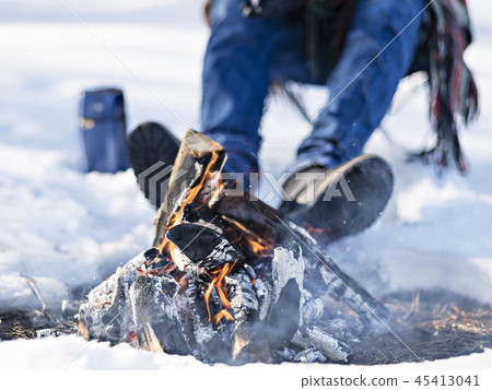 Crop traveler warming feet at bonfire. 45413041