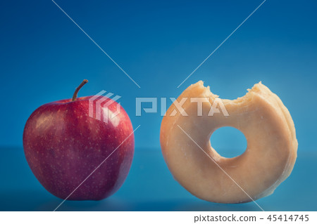 Bitten donut and whole red apple.  45414745