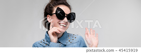 Young brunette girl in black glasses. Cat glasses. The hair is gathered in a bun. The girl put a Young brunette girl in black glasses. Cat glasses. The hair is gathered in a bun. The girl put a 45415919
