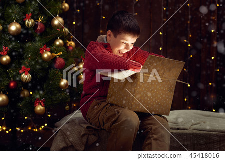 boy sitting with gift box near christmas tree 45418016
