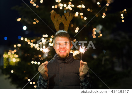 People, holidays and Christmas concept - young funny man in christmas deer costume with bengals People, holidays and Christmas concept - young funny man in christmas deer costume with bengals 45419347
