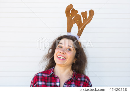 Portrait of happy smiling woman with Christmas deer horns on white background Portrait of happy smiling woman with Christmas deer horns on white background 45420218
