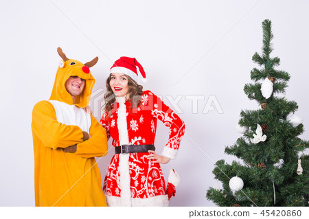 People, family and christmas concept - lovely couple in christmas costumes near christmas tree on 45420860