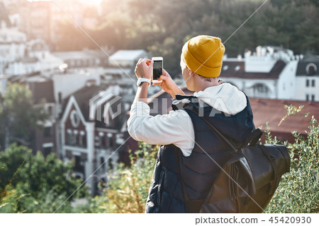 Young man tourist taking photo of of retro buildings. Rear view 45420930