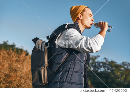 Young stylish tourist blogger is drinking water while walking at the mountains 45420990