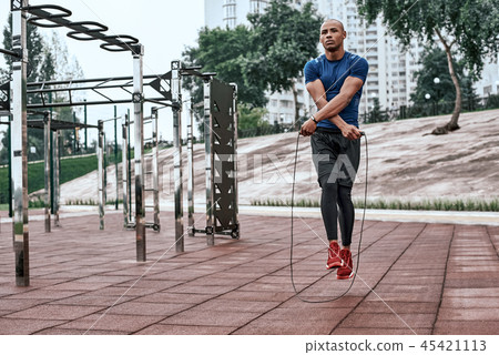 Muscular african man is skipping rope. Portrait of muscular young man exercising Muscular african man is skipping rope. Portrait of muscular young man exercising 45421113