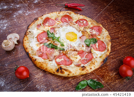 Pizza with sausage and egg on a wooden table 45421419