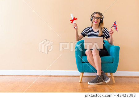 Young woman holding a diploma and UK flag with her laptop 45422398