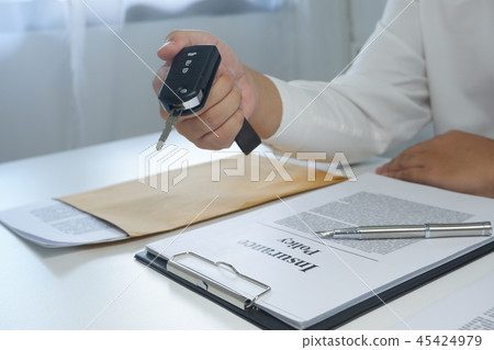 hand hand giving a car key, document on table 45424979
