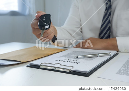 hand hand giving a car key, document on table 45424980