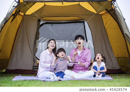 Family having picnic outdoors. Parents with two children relax in the park. Concept of happy family relations and carefree leisure time. 262 Family having picnic outdoors. Parents with two children relax in the park. Concept of happy family relations and carefree leisure time. 262 45428574