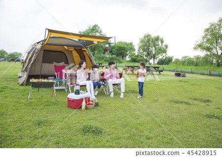 Family having picnic outdoors. Parents with two children relax in the park. Concept of happy family relations and carefree leisure time. 225 Family having picnic outdoors. Parents with two children relax in the park. Concept of happy family relations and carefree leisure time. 225 45428915