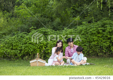 Family having picnic outdoors. Parents with two children relax in the park. Concept of happy family relations and carefree leisure time. 113 45429016