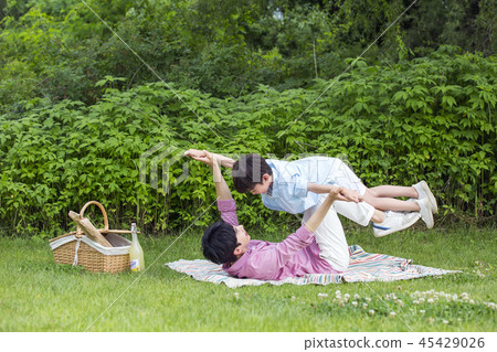 Family having picnic outdoors. Parents with two children relax in the park. Concept of happy family relations and carefree leisure time. 107 Family having picnic outdoors. Parents with two children relax in the park. Concept of happy family relations and carefree leisure time. 107 45429026