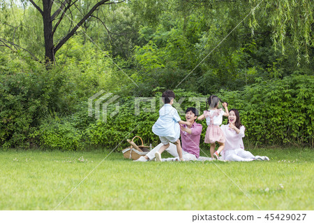 Family having picnic outdoors. Parents with two children relax in the park. Concept of happy family relations and carefree leisure time. 098 Family having picnic outdoors. Parents with two children relax in the park. Concept of happy family relations and carefree leisure time. 098 45429027